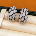 Vue détaillée de boucles d'oreilles en C avec motif nid d'abeille noir et zircons. - Argent