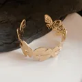 Detailed view of a gold-plated butterfly cut-out cuff bracelet on a minimalist background. - Gold (3#)