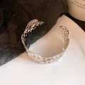 Macro view of a silver metal open cuff bracelet with intricate pleated wing patterns - Silver (10#)