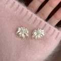 Close-up view of delicate chamomile flower stud earrings against a soft pink sweater - Silver Earring Post Style / Silver White