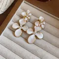 Macro view showing the exquisite white enamel petals and rhinestone center of flower earrings - Silver Earring Post-White