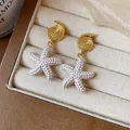 Detalle de pendientes de concha chapados en oro de 18k y estrella de mar blanca - Poste Plata Oro Estrella de Mar Topos (Chapado Oro) / Blanco