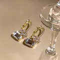 Nahaufnahme eleganter goldener Creolen mit funkelnden floralen Zirkonia - Klarer Zirkonia Blumenstil / 925 Silberstecker / Gold-Weiß