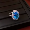 Detailed close-up of a sparkling oval blue zircon ring with a halo of accent stones - Ring / Blue