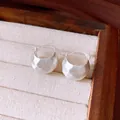 Nahaufnahme von eleganten gebürsteten silbernen halbrunden Creolen in einer Box - Ohrbuckle / Silber