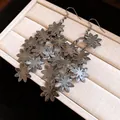 Primo piano di orecchini pendenti a fiori in metallo con trame dettagliate dei petali. - Canna di fucile
