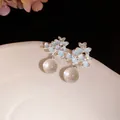 Détail de boucles d'oreilles fleurs en émail bleu clair avec gouttes en boule de verre - Bleu
