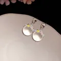 Gros plan de boucles d'oreilles fleurs avec pierres translucides et émail coloré. - Coloré