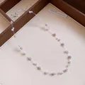 Detail shot of an elegant pearl and sparkling rhinestone necklace on transparent fishline - White