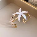 Close-up of white enamel starfish ornaments on a gold-plated open cuff bangle - Starfish Open Bracelet / White