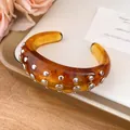 Detail of amber resin open bangle with silver-tone round rivets decoration - Bangle / Brown