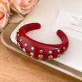 Macro view of a red resin cuff bracelet with silver studs on an elegant display tray - Bangle / Red