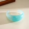 Close-up of a light blue translucent acrylic cuff bracelet with unique marble texture - Sky Blue