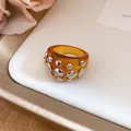 Close-up detail of a chunky amber resin ring decorated with silver metal rivets. - Ring (Silver-Coffee-Iron) / Brown