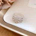 Close-up of cream resin ring with sparkling rhinestone accents on a white tray - Ring / Beige