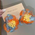 Close-up detail of handmade chiffon flower earrings in vibrant orange and blue tones. - Silver Post - Blue-Yellow-Orange