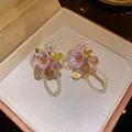 Close-up of floral stud earrings with purple petals, pearls, and cat's eye beads in a box - Flower Style / Purple and White