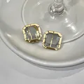Exquisite close-up detail of minimalist square glass stud earrings with gold plated frame - Square Glass Style / Gold