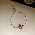 Detail view of a shimmering silver clover bracelet with red petals and zircon accents. - Clover Bolo Bracelet / Silver/Rose Red