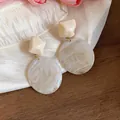 Dettaglio di orecchini pendenti in resina geometrica crema con motivo marmorizzato chic - Bianco