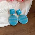 Dettaglio di orecchini in resina marmorizzata blu con pendenti geometrici - Blu