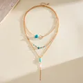 Detail view of a vintage multi-layer gold necklace with turquoise stones and beads - Gold