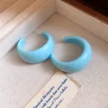 Vue détaillée de boucles d'oreilles en résine bleue en forme de C dans un écrin à bijoux - Bleu