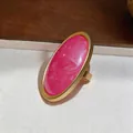 Detailed close-up of a minimalist gold oval ring with a large vibrant fuchsia resin stone - Oval Ring / Gold Frame / Pink