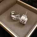 Close-up of silver-tone C-shaped earrings with unique wrinkled texture inside a box. - Silver Earring Post Style / Silver