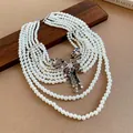 Detailansicht einer mehrlagigen Perlenkette mit einem funkelnden Strass-Schmetterling. - Silberweiß
