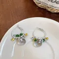 Dettaglio di orecchini a cerchio con perline e ciondolo a sfera grigio traslucido - Verde-Giallo