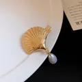 Close-up of a gold seashell hair clip with a teardrop pearl pendant on a white plate - Water Drop Artificial Pearl Pendant Style / Gold