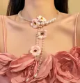 Gros plan d'un collier élégant en fleurs roses avec glands en perles et perles de cristal. - Collier-Blanc-Rose
