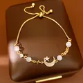 Close-up of elegant gold moon and star bracelet with cat's eye beads on jewelry box - Star Moon Style / Gold