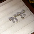 Close-up view of elegant silver bow earrings with sparkling zircons and pearls - Silver