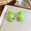 Détail des boucles d'oreilles clous en résine vert citron en forme de C doré. - Vert