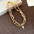 Dettaglio macro di una collana vintage dorata a doppio strato con ciondolo a cuore. - Collana / Oro