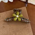 Detail view of a brown floral fabric hair claw clip with a green resin flower center. - Green Floral