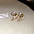 Macro detail of sparkling strawberry pearl stud earrings with elegant gold finish - White
