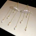 Detail view of elegant shell and freshwater pearl tassel earrings with gold chains for women. - Tassel Earrings (HE32227) / Gold-White
