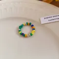Detailed macro view of a bohemian colorful rice beaded ring displayed on a white plate - Ring / Colorful