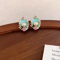 Vista dettagliata di eleganti orecchini floreali in smalto azzurro con perle crema - Ago d'Argento-Verde-Viola