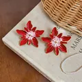 Detailed macro view of vibrant red and white enamel flower stud earrings with gold edges - Gold Style / Red