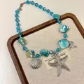Detailed view of beach-style necklace with blue beads and silver starfish charms - Blue