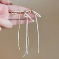 Vue détaillée de longues boucles d'oreilles en ruban blanc avec des accents dorés. - Style de Gland Long (HE32551) / Blanc