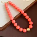 Detailed view of chunky coral pink bead necklace with single gold accent bead. - Necklace / Pink