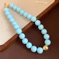 Close-up of chunky light blue bead necklace with a single gold bead accent - Necklace / Light Blue