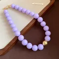 Statement chunky lavender purple beaded necklace with a central gold metallic orb accent - Necklace / Light Purple
