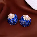 Detail view of vintage palace-style stud earrings with blue gems and central pearl - Gold Base / Dark Blue