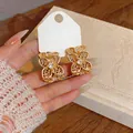 Detalle de pendientes de flores huecas doradas en forma de C con circonitas brillantes - Dorado